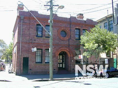 Western facade of Millers Point Post Office building fronting Kent Street showing front brickwork detail and arched front entry porch.    Note the multiple pane sash windows, oculus at centre, brick string courses and stylised parapet.