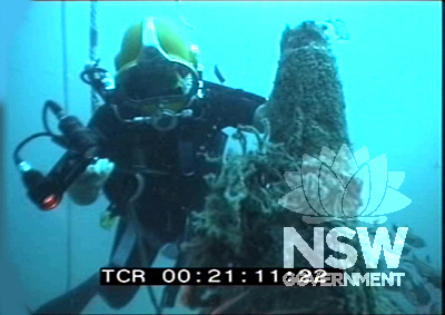 M24. Royal Australian Navy Clearance Diver inspecting remains of conning tower. View from bow casing.