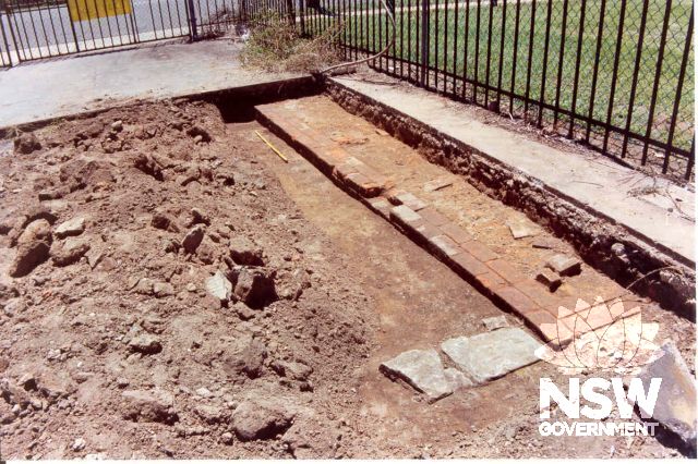 Partially excavated sandstone capped drain and sandstock brick footing thought to be associated with the circa 1790 military barracks. The footing was uncovered during archaeological testing by Casey and Lowe Pty Ltd