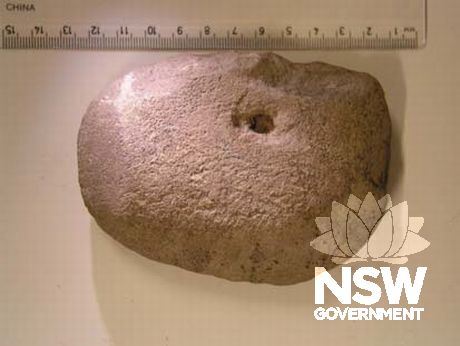 Axe (114 x 86 x 14mm in size) found during excavation of the Meriton Building Site . The raw material the axe is made of has not been determined but it is likely to be a silcrete/quartzite. There is an anvil hole on one side.