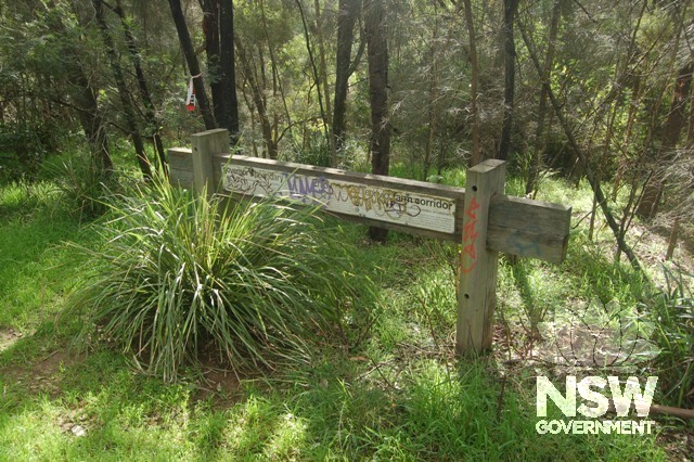 Signage about bush care erected in 2000 on the south bank of Toongabbie Creek in Oakes Reserve, looking North West. The vegetation along the south bank of the creek is shown behind the sign