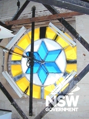 Interior view looking south of the clock tower, showing the internal framework, fluorescent lighting and clock face.  The clock faces are currently decorated with blue and yellow adhesive film.