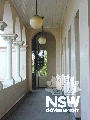 View looking south of the first-floor verandah to the cast-iron stair accessing the clock tower, showing the verandah columns, pendant lighting and squared openings.
