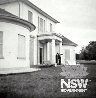 Historic photo Two unidentified men under front porch at Denham Court, Campbelltown - undated, held in Campbelltown City Library (Ref 001\001580)