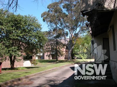 1 Fleet Street, Parramatta. Two storey brick building behind trees, to south  of brick wall and wooden gate.