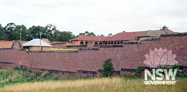 Parts of the colonnaded verandah of Ward 22, a disused former maximum security ward, glimpsed across the high north-east wall of the prison, looking south. (Doring Neg.407.30a) (also see supplementary images)