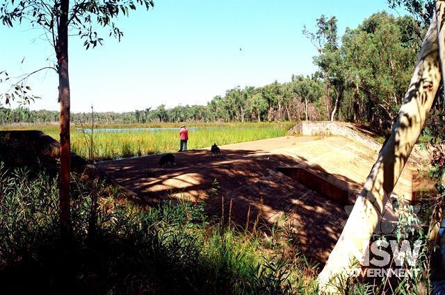 The dam spillway viewed from the north-east. The water of the reservoir can be seen in the centre background. The dam earth wall continues off to the right (west), covered with trees. (Doring Neg.481.31)