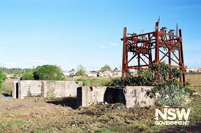 Base of the cut-off iron headframe, viewed from N-W & looking towards the backs of houses in Wilson Street. In the foreground are several concrete foundation blocks for machinery (to be identified). (Doring Neg.304.15)