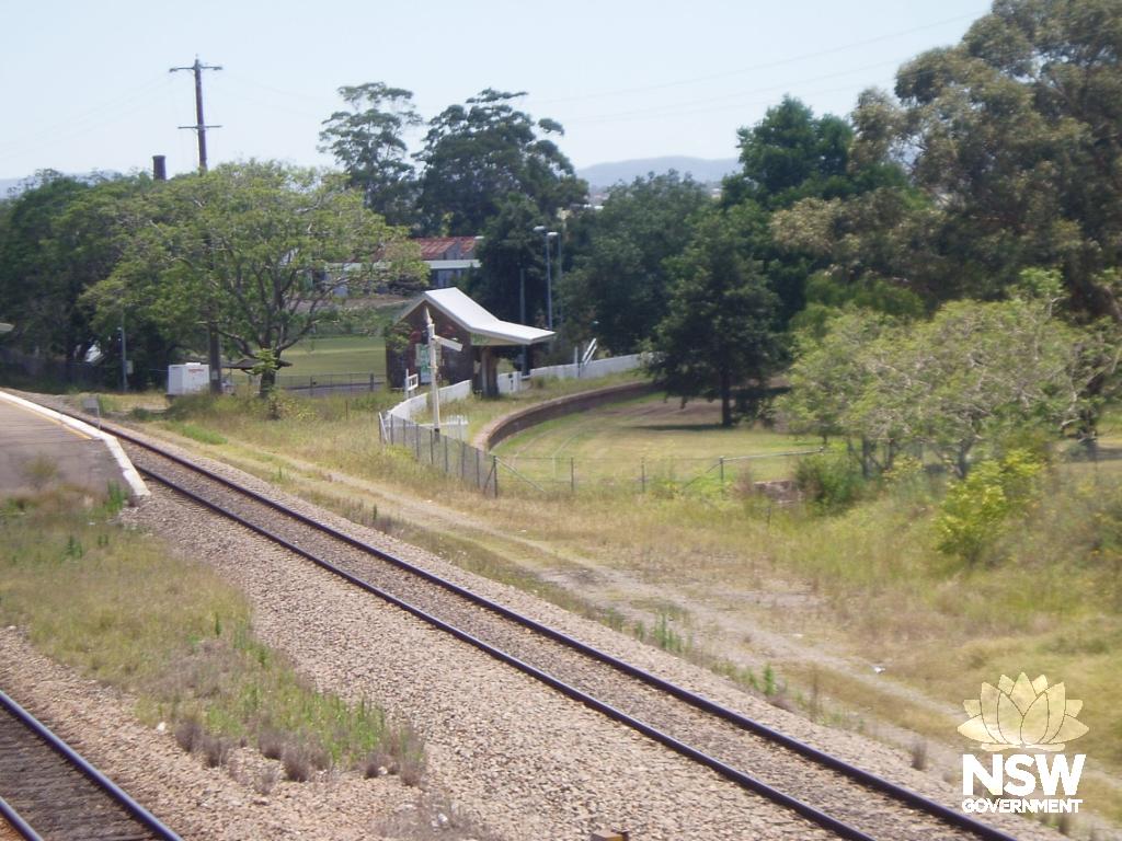 View of former Morpeth branch line from main Newcastle to Maitland line, showing station building, fence and landscaping