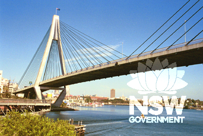 Main span with Anzac emblem visible at midspan, and old Glebe Island Bridge opening span visible on left.
