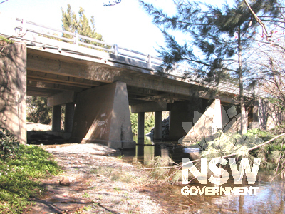 Oblique view upstream showing mass concrete piers and abutments of original crossing, reinforced concrete deck, and widening using prestressed concrete planks in background