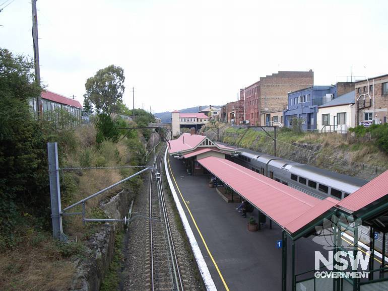 Station building with timber buildings to Sydney end, footbridge in background