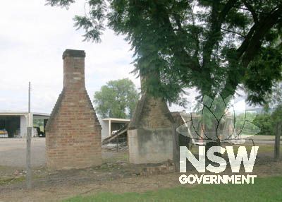 Propped remains of slab cottage with brick chimney to side