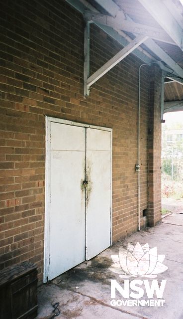View of explosives storehouse showing the double entry door in the west wall and the large roof overhang.