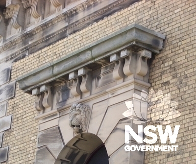 Close view of stone detailing on facade and lions head above central entrance way