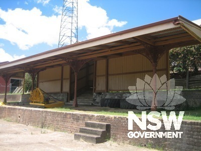 Covered platform elevated on a brick plinth, with wrought-iron columns and timber siding.