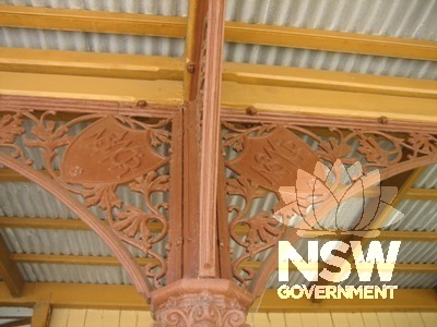 Platform wrought-iron column capital and detail with shield and foliage.