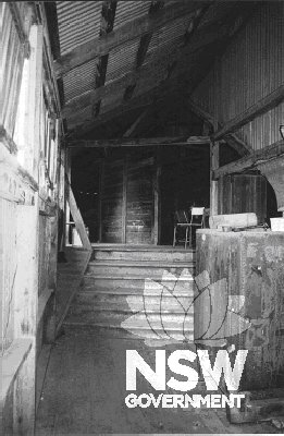 Stairs leading to the upper levels of the shed where piece pickings were sorted and dropped through a chute for bailing (2002).  The water tank to the right collected roof water for the shearers to drink.