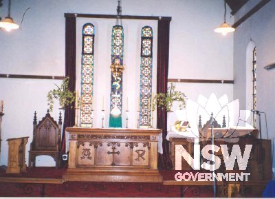 Interior of All Saints Anglican Church Condobolin - altar with tabernacle furniture and stained glass windows.